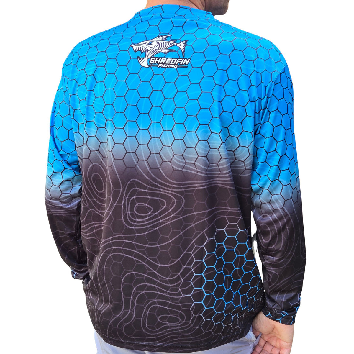 Back of ShredFin HexCast Amalfi Coast Fade long sleeve performance fishing shirt featuring blue hex pattern, black topo fade, and upper back logo.