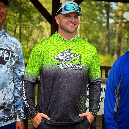 Man wearing a ShredFin HexCast Chartreuse Black Fade hooded performance fishing shirt outdoors.